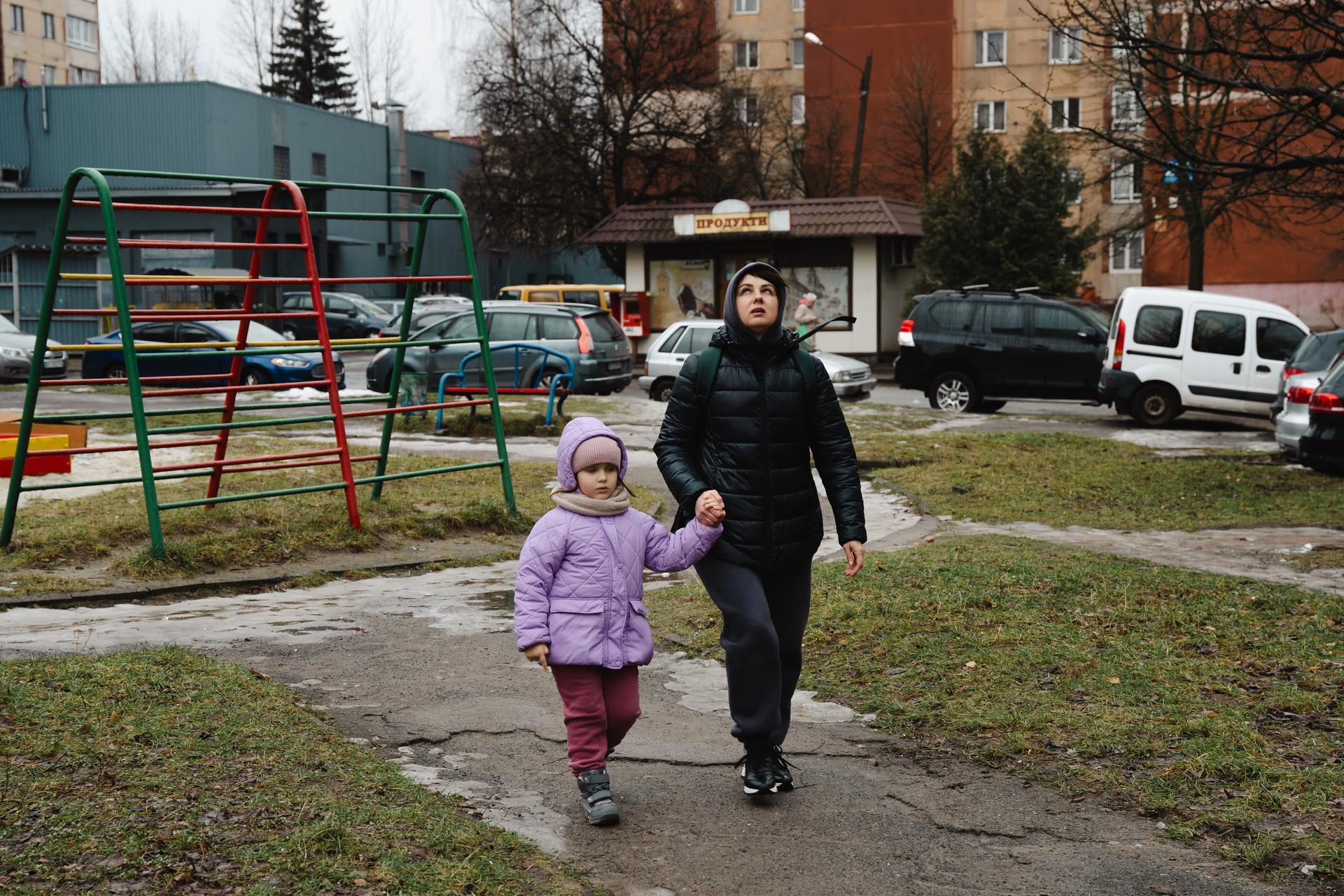 Vitalina looks up at the sky as an air raid warning goes off while out for a walk near their apartment in Lviv, Ukraine. February 3, 2024. (photo/Jeff Kennel)