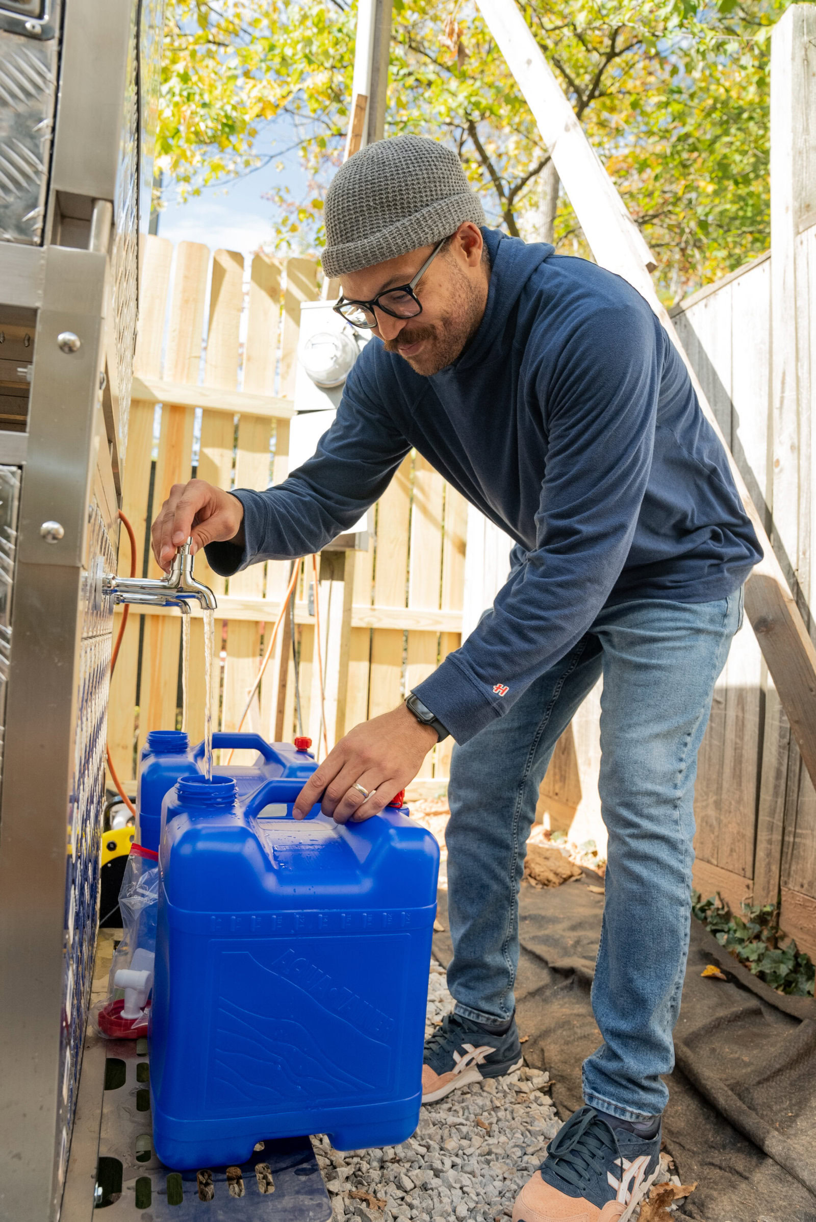 After Hurricane Helene cut off power and water, Jerome filled containers with clean water for his family from an AquaBlock water filtration system installed by Americares in partnership with the Planet Water Foundation. (Photo/Americares)