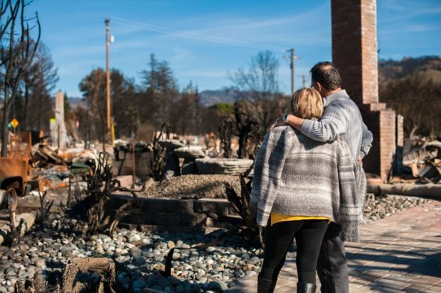 A couple look at the remains of their house after a fire.